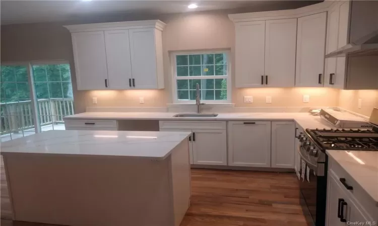 Kitchen with sink, white cabinets, wood-type flooring, and gas stove