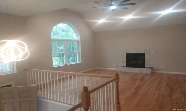 Unfurnished living room featuring a wealth of natural light, ceiling fan, vaulted ceiling, and hardwood / wood-style floors