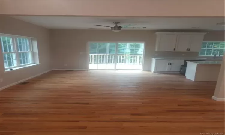 Unfurnished living room featuring a wealth of natural light, wood-type flooring, and ceiling fan