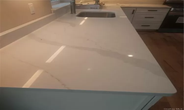 Room details featuring white Quartz Counter top cabinetry,, stove, dark hardwood / wood-style flooring, and sink