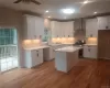 Kitchen with gas range, white cabinets, ceiling fan, and wall chimney exhaust hood