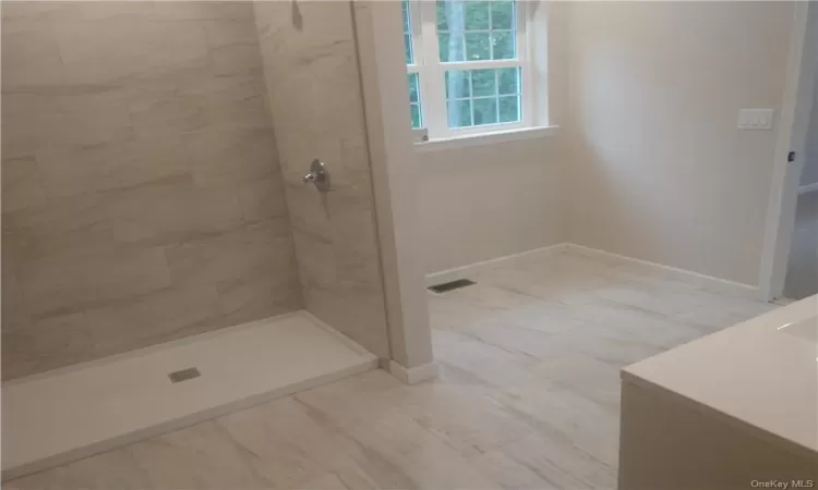 Bathroom featuring tiled shower and tile flooring