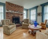 Front living room has full length windows with wide colonial moldings and hardwood floors.  Brick wood burning fireplace is one of three in this lovely home.