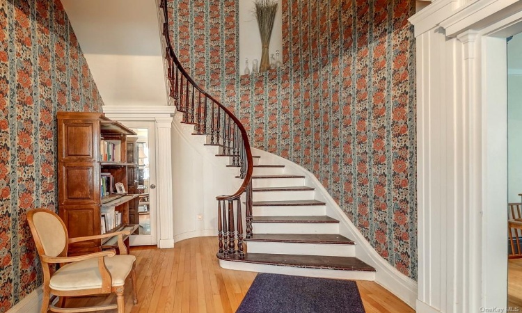 Wide formal entry with gorgeous mahogany railed curved staircase.  Take note of the beautiful molding as well. To the right is one of the two formal living rooms.