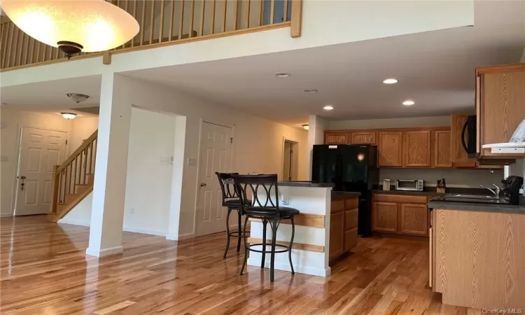 Kitchen featuring a breakfast bar, black fridge, sink, and light wood-type flooring