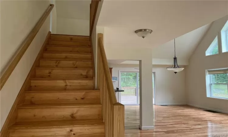 Stairs with high vaulted ceiling and light hardwood / wood-style floors