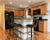 Kitchen with hardwood flooring, kitchen peninsula, a kitchen bar, and black appliances