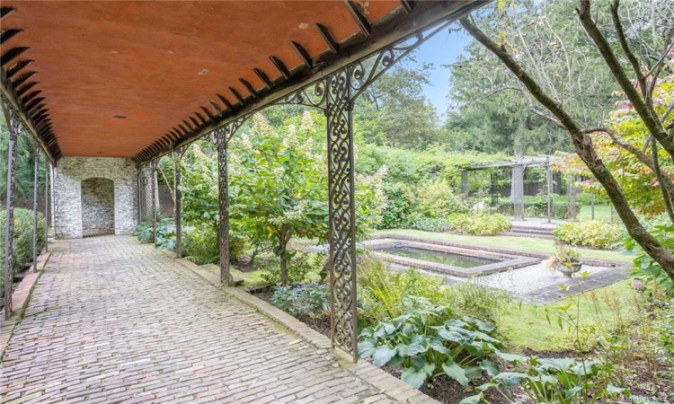 The vintage brick and wrought iron portico showcase the reflecting pond and gardens