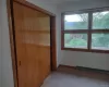 Unfurnished bedroom featuring carpet flooring, a baseboard radiator, a closet, and multiple windows