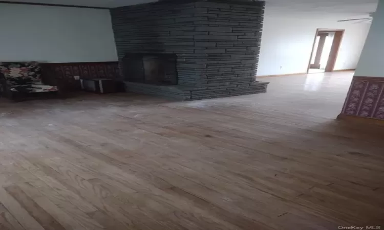 Unfurnished living room featuring ceiling fan, a fireplace, and hardwood / wood-style flooring