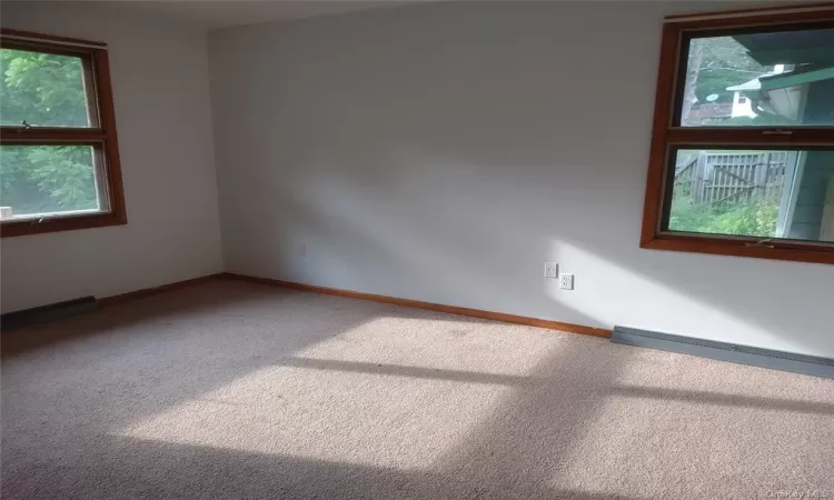 Carpeted spare room featuring baseboard heating and plenty of natural light