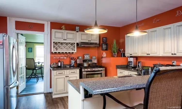 Kitchen with hanging light fixtures, sink, dark hardwood / wood-style flooring, and stainless steel appliances