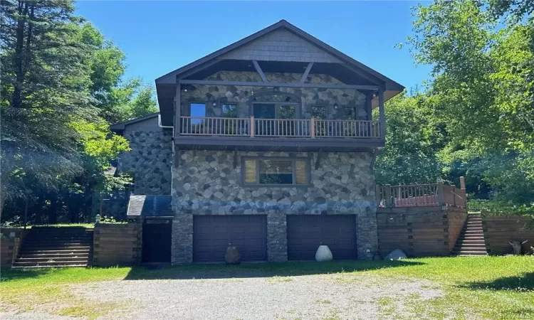 View of front of home with a garage, a front lawn, and a balcony