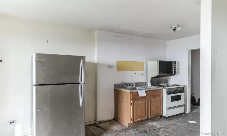 Kitchen featuring white range with gas stovetop, stainless steel refrigerator, and sink