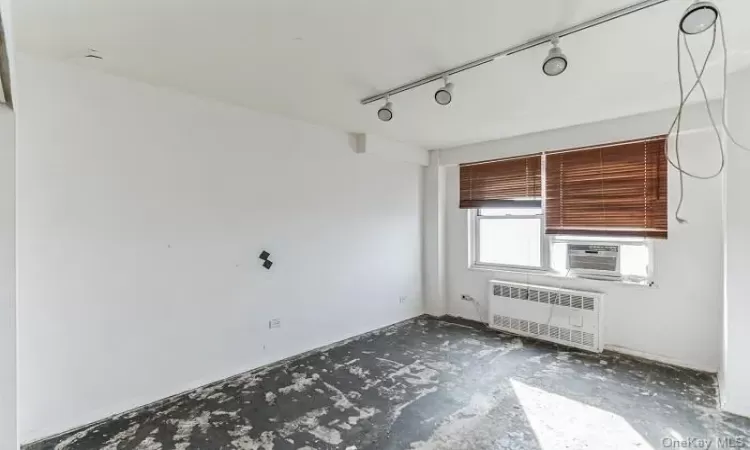 Spare room featuring radiator, rail lighting, and cooling unit