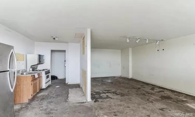 Kitchen with gas range gas stove, rail lighting, stainless steel fridge, and sink