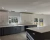 Kitchen with white cabinets, light stone countertops, sink, and light tile patterned floors