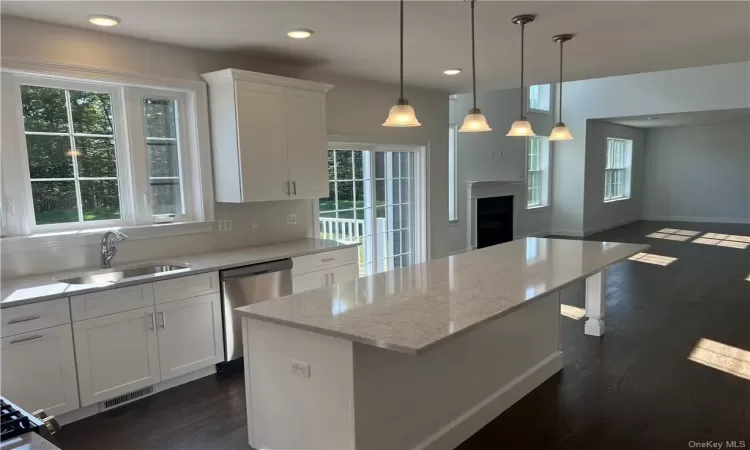 Kitchen featuring a kitchen island, dark hardwood / wood-style floors, pendant lighting, sink, and white cabinetry