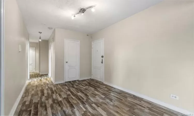 Empty room with a textured ceiling and dark hardwood / wood-style flooring