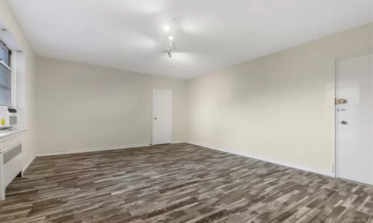 Spare room with radiator heating unit and dark hardwood / wood-style floors