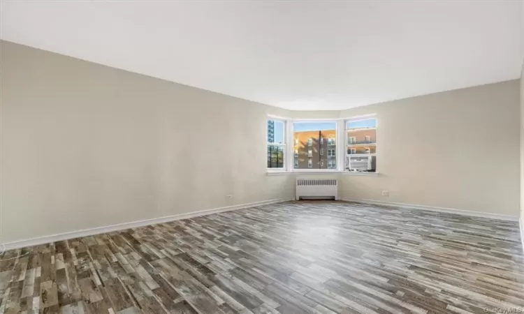 Unfurnished room featuring radiator heating unit and wood-type flooring