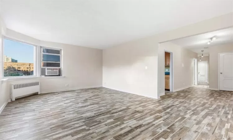 Unfurnished room featuring radiator heating unit, cooling unit, and light hardwood / wood-style flooring