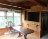 Dining room with wood walls, a baseboard radiator, a notable chandelier, wood-type flooring, and lofted ceiling with beams