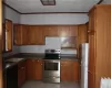 Kitchen with a textured ceiling, stainless steel electric range, dishwasher, sink, and white refrigerator