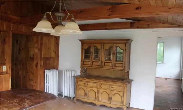 Unfurnished dining area with radiator heating unit, lofted ceiling with beams, a chandelier, and wooden ceiling