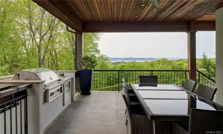 Outdoor dining room with built in Lynx BBQ Grill and stairs to patio pool and garden