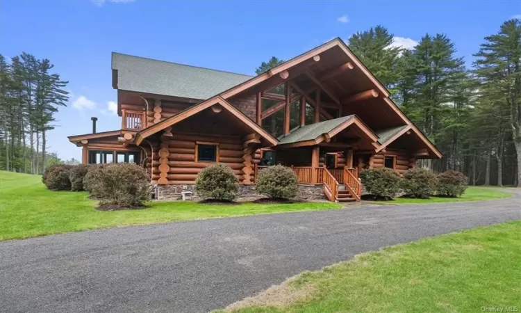 Log-style house with a porch and a front lawn