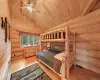 Bedroom featuring light wood-type flooring, wood ceiling, log walls, ceiling fan, and high vaulted ceiling