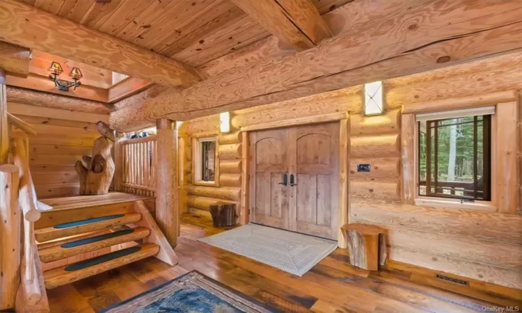 Foyer entrance with beamed ceiling, hardwood / wood-style floors, and rustic walls