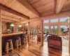 Living room with wooden ceiling, beamed ceiling, french doors, log walls, and light hardwood / wood-style flooring