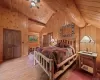 Bedroom with vaulted ceiling with beams, wood ceiling, wood walls, ceiling fan, and wood-type flooring