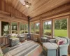 Sunroom / solarium with a wood stove, lofted ceiling, ceiling fan, and wood ceiling