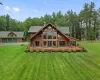 Back of house with a garage, a lawn, and a deck