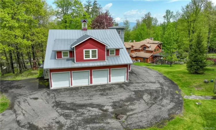 View of front of guest house with a front yard and a garage