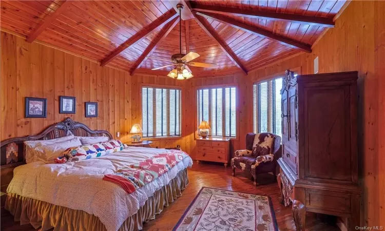 Bedroom with wood walls, hardwood / wood-style floors, lofted ceiling with beams, and wood ceiling