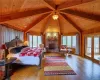 Bedroom with a stone fireplace, multiple windows, hardwood / wood-style flooring, and wood ceiling