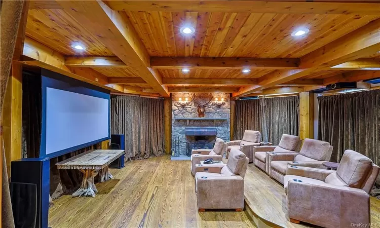 Cinema room featuring flooring, a stone fireplace, beamed ceiling, and wood ceiling