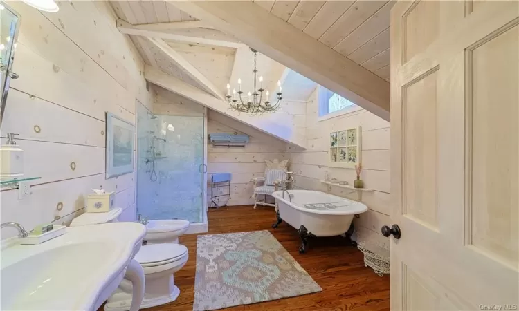 Full bathroom with hardwood / wood-floors, lofted ceiling with beams, sink, wood walls, and toilet