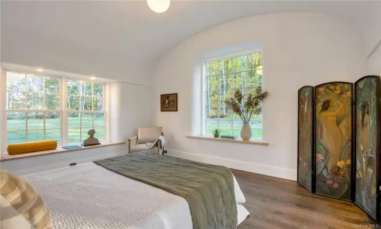 Bedroom with hardwood with barrel vaulted ceiling and window seats