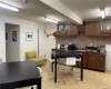 Kitchen featuring sink, backsplash, dark brown cabinets, and light tile floors