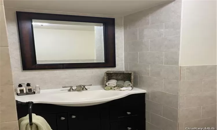 Bathroom featuring large vanity, tasteful backsplash, and tile walls