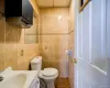 Bathroom with tile flooring, tile walls, toilet, and vanity