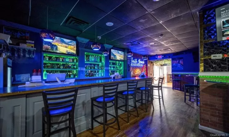 Bar with dark hardwood / wood-style flooring and a drop ceiling