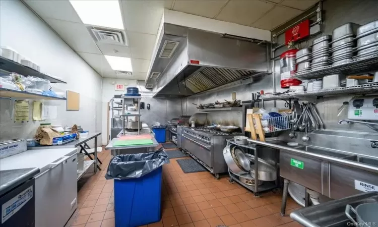 Kitchen with tile walls, a drop ceiling, stainless steel counters, tile flooring, and appliances with stainless steel finishes