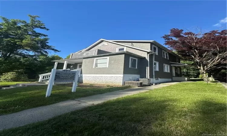 View of front of house featuring a front yard and central AC unit