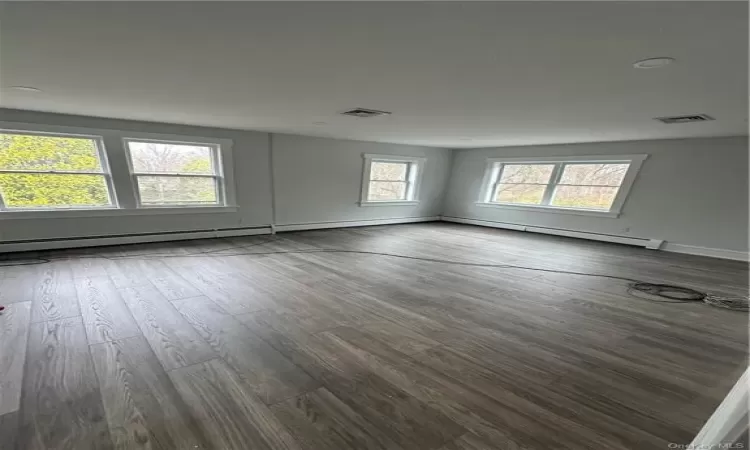 Empty room featuring wood-type flooring and a baseboard radiator